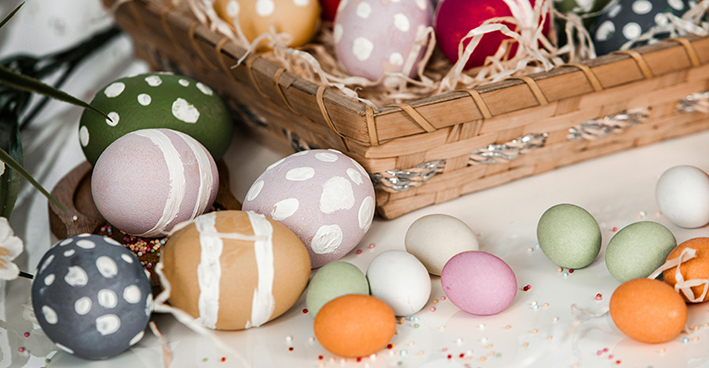 målade ägg i en korg och framför korgen