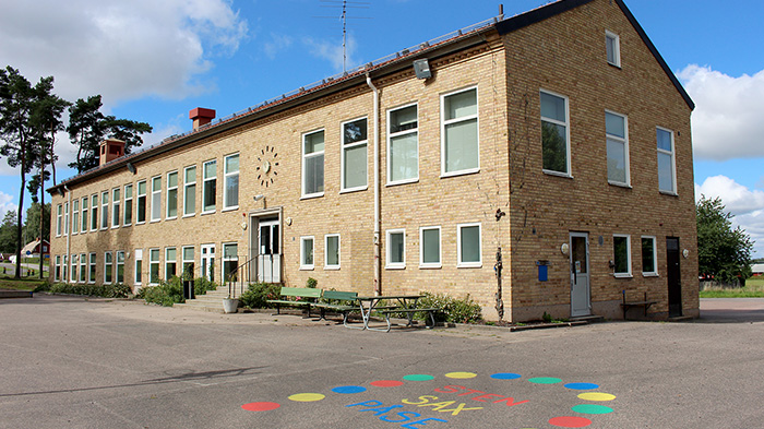 Tvåplanshus i gult tegel. Skolgård framför.